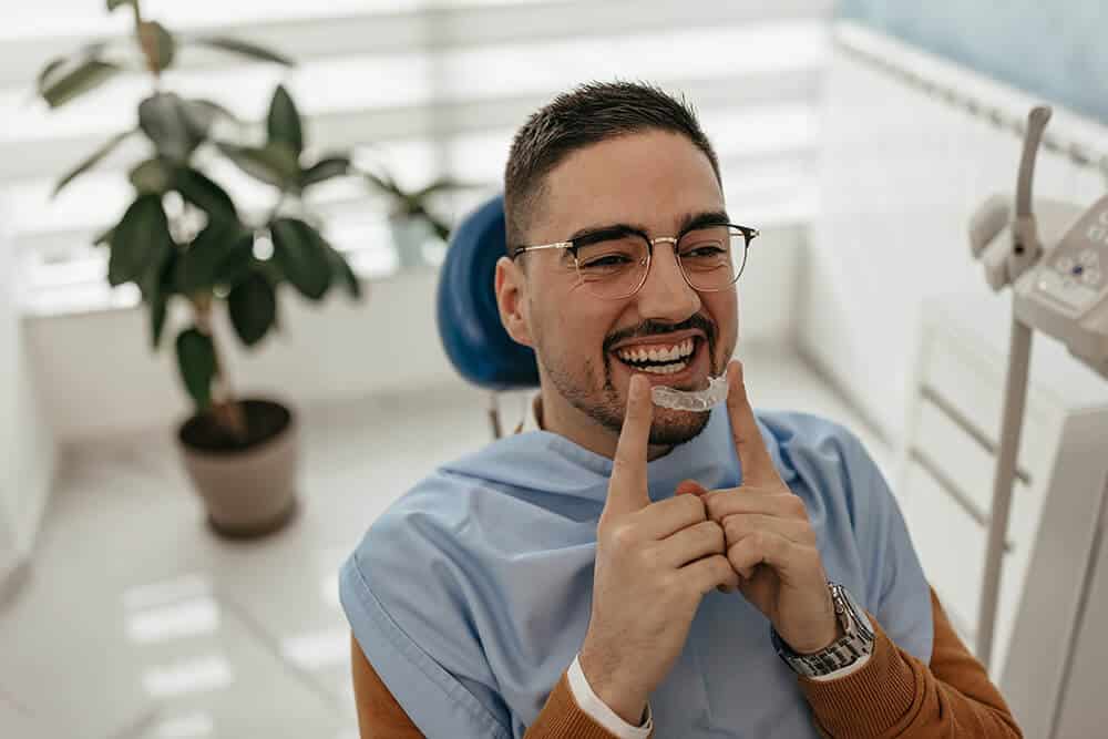 man putting a clear aligner onto his teeth