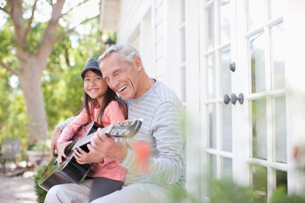 Older man and granddaughter playing guitar